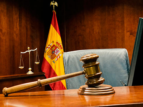 Mazo de juez sobre estrado con bandera de España y balanza de la justicia